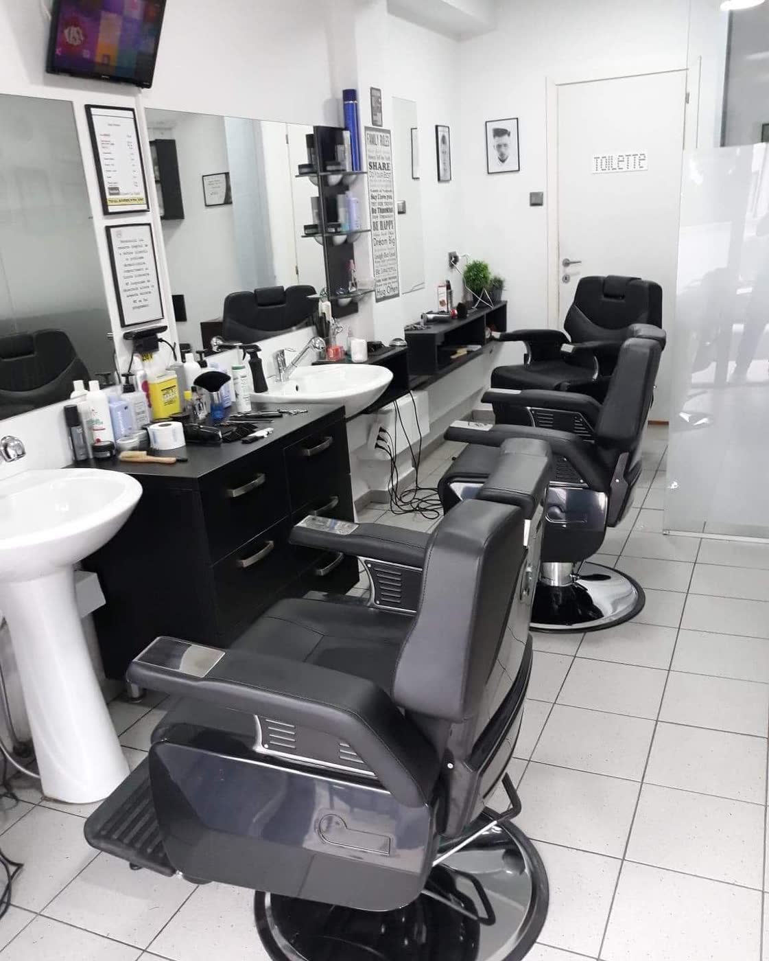 Scaunele negre de frizerie și chiuvetele albe din salonul La Vasile
